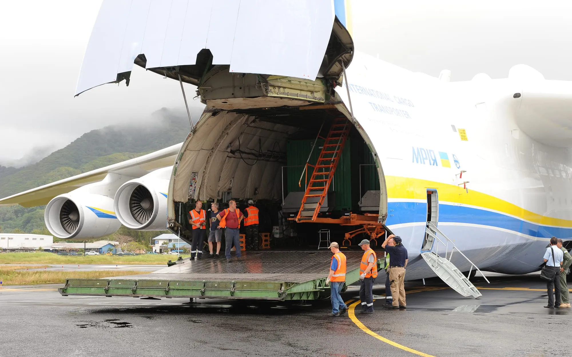 Large cargo aircraft with its nose door open, unloading freight on the airport apron