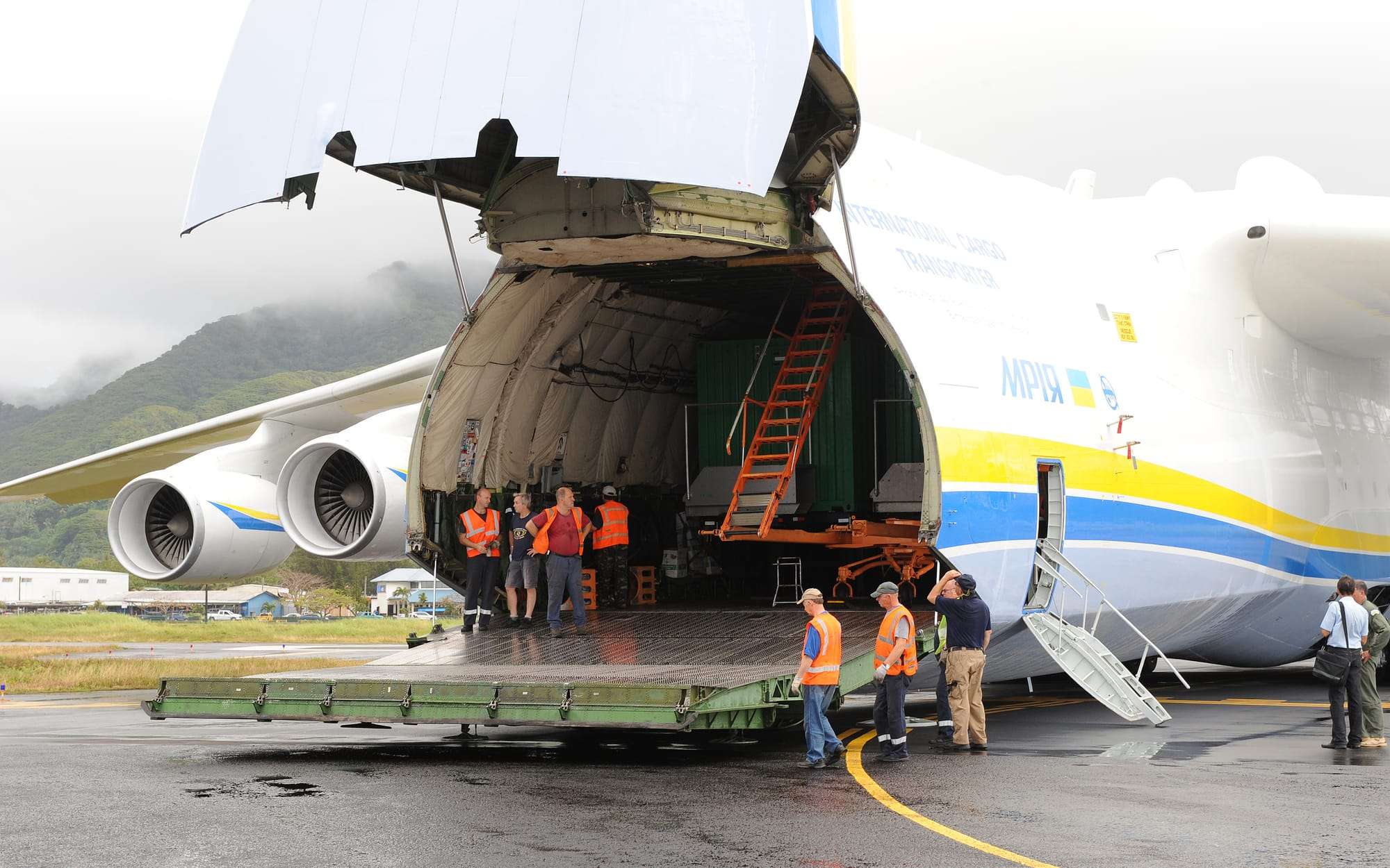 Large cargo aircraft with its nose door open, unloading freight on the airport apron