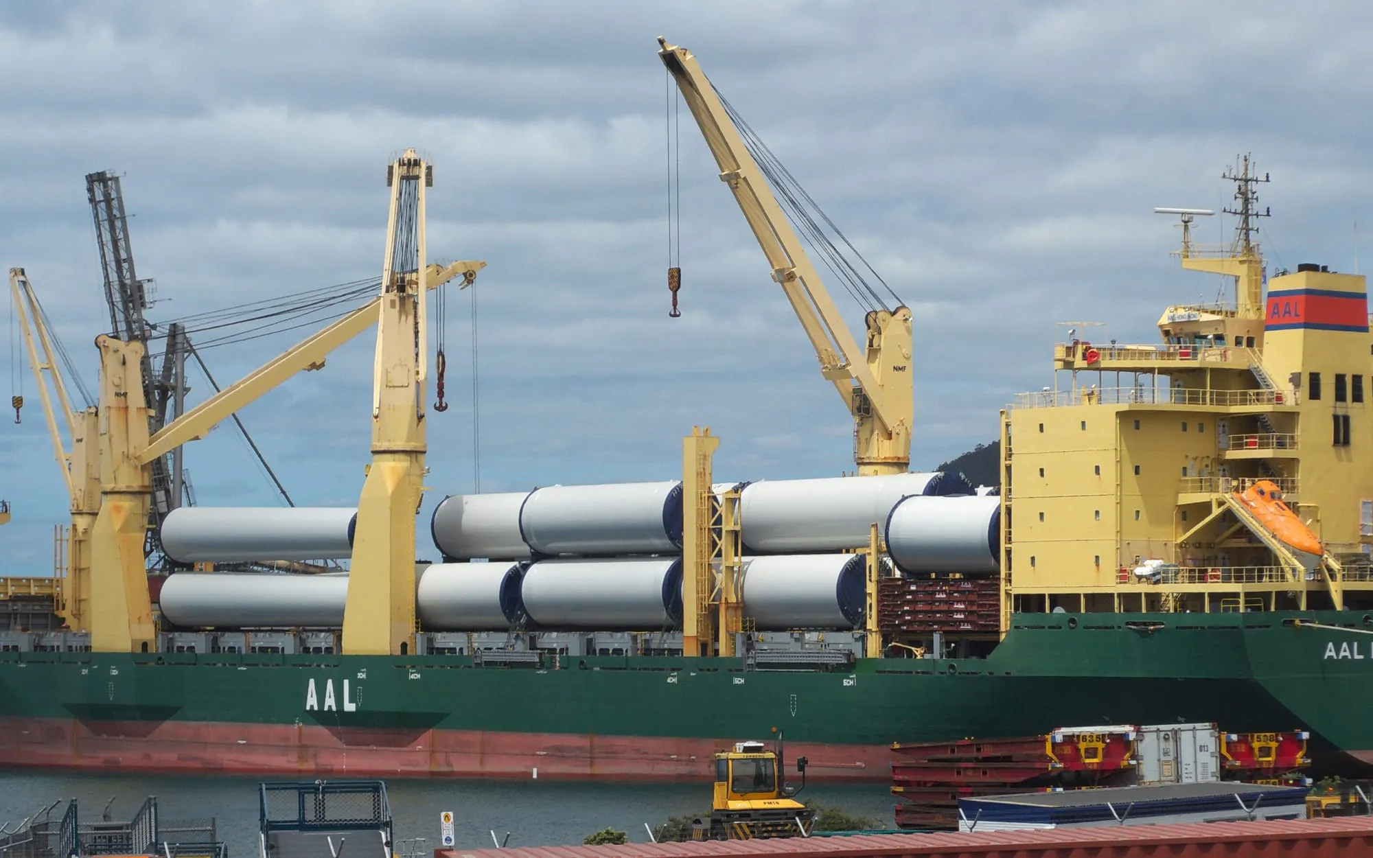 Heavy industrial machinery being lifted onto a ship by crane